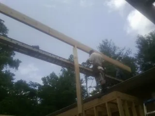 Carpenter setting a ridge beam over a new addition frame — Ice Dam Removal by Roofing Brothers in College Park