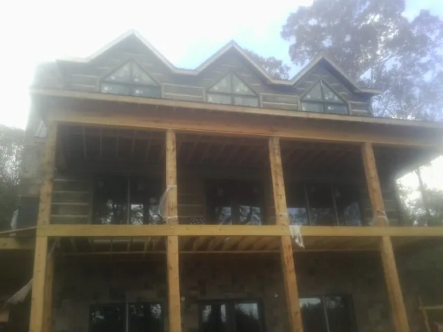 Dormers and porch framing on a large log home under construction — Roof Coating work by our crew in College Park