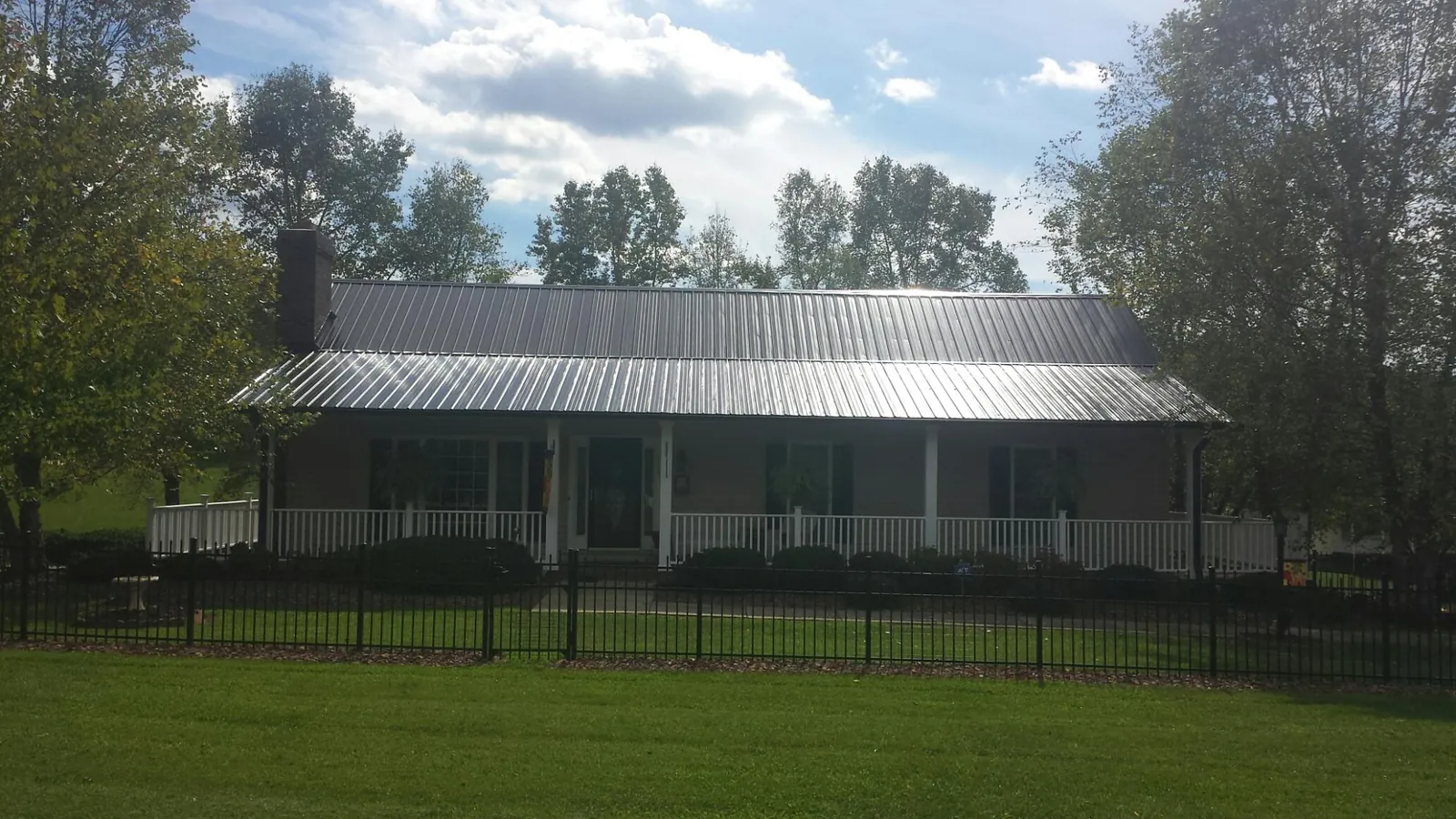 Gray metal roof on a brick ranch with a full width front porch — Gutter Guard Installation work by our crew in College Park