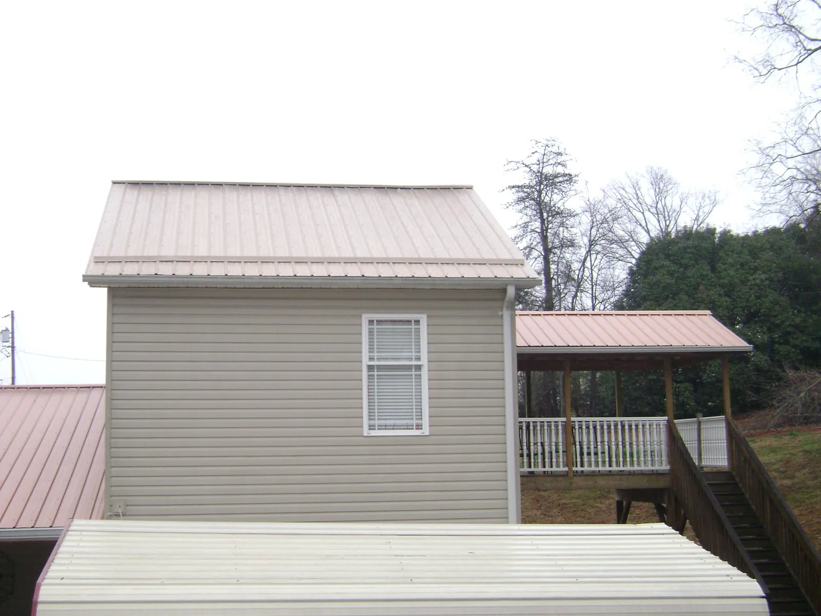 Tan metal roofs on a two story addition and attached porch, from a Roof Replacement job in College Park