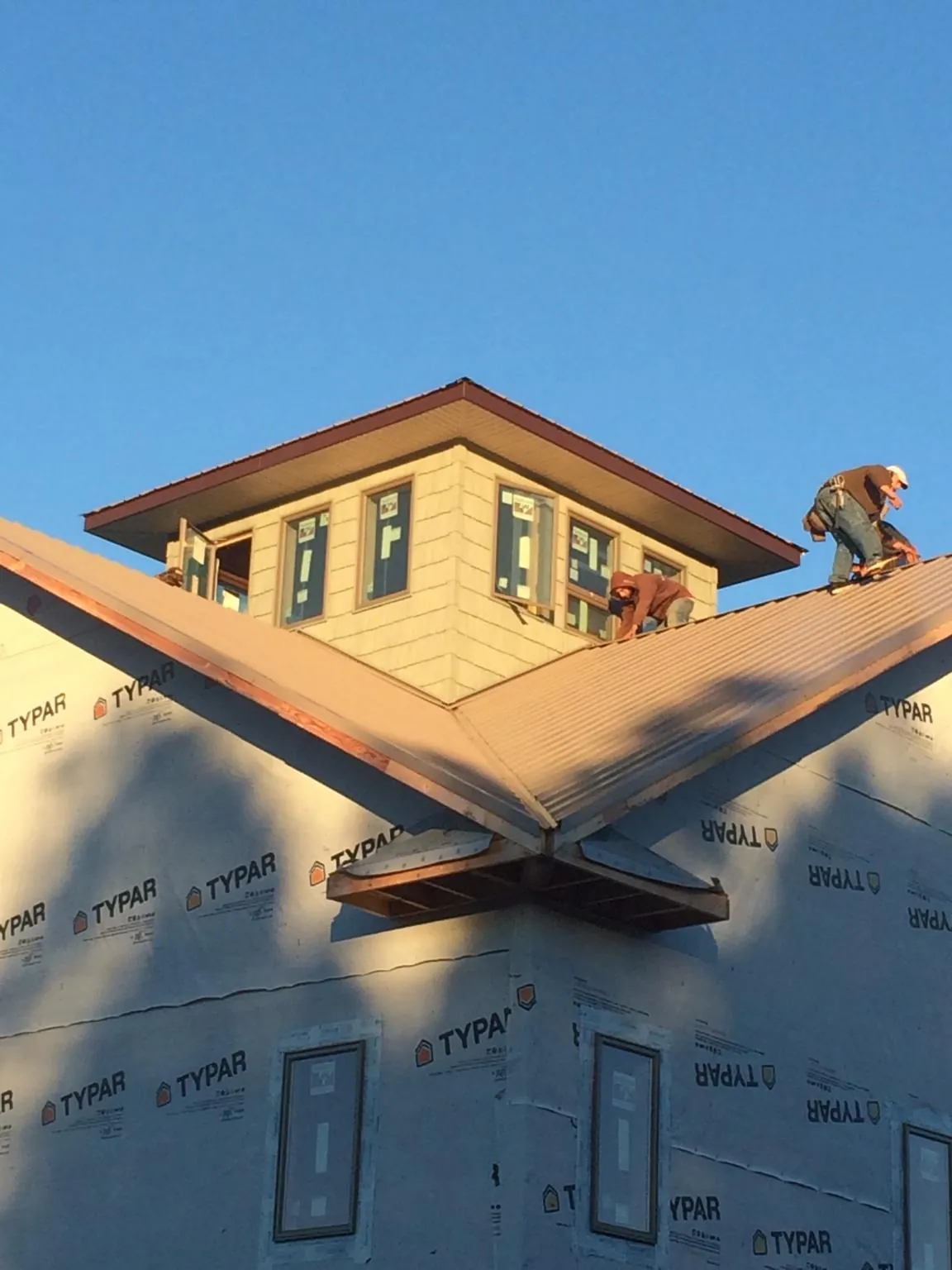 Roofers working around a rooftop cupola on a new metal roof at sunset — Roof Waterproofing in College Park by Roofing Brothers